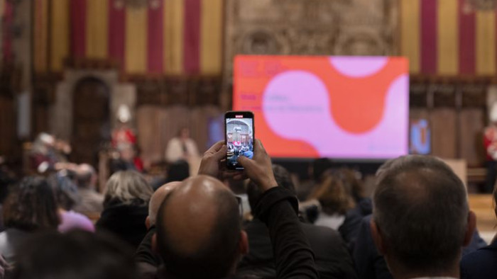 Un home del públic fa un vídeo amb el telèfon mòbil durant l’acte de presentació de la Biennal Ciutat i Ciència 2022, al Saló de Cent de l’Ajuntament de Barcelona